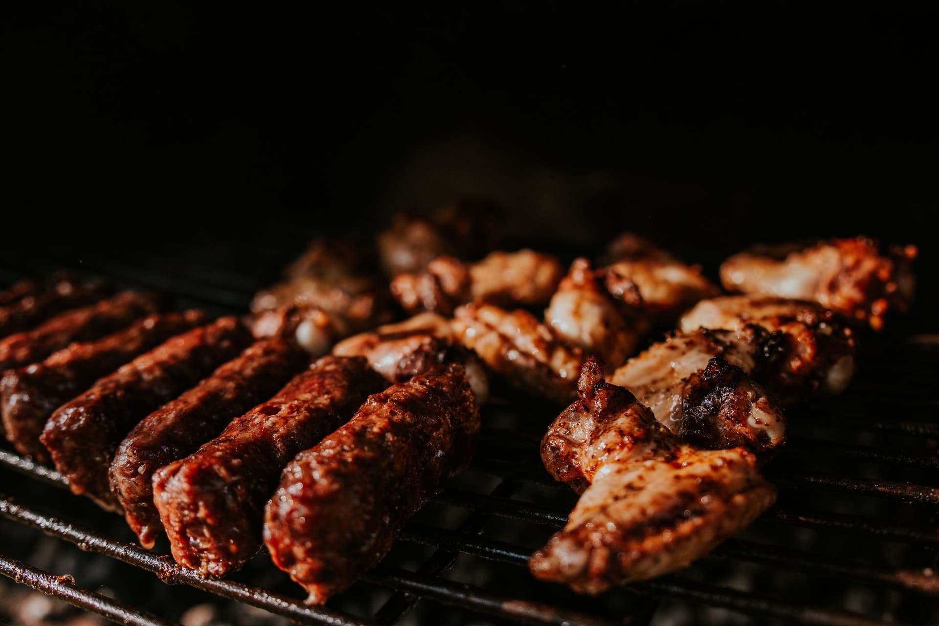 Sausages and chicken wings cooking on a barbecue grill