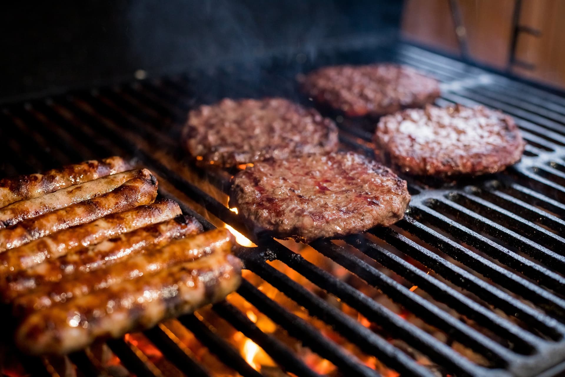 Beef burgers and sausages cooking on a barbecue grill