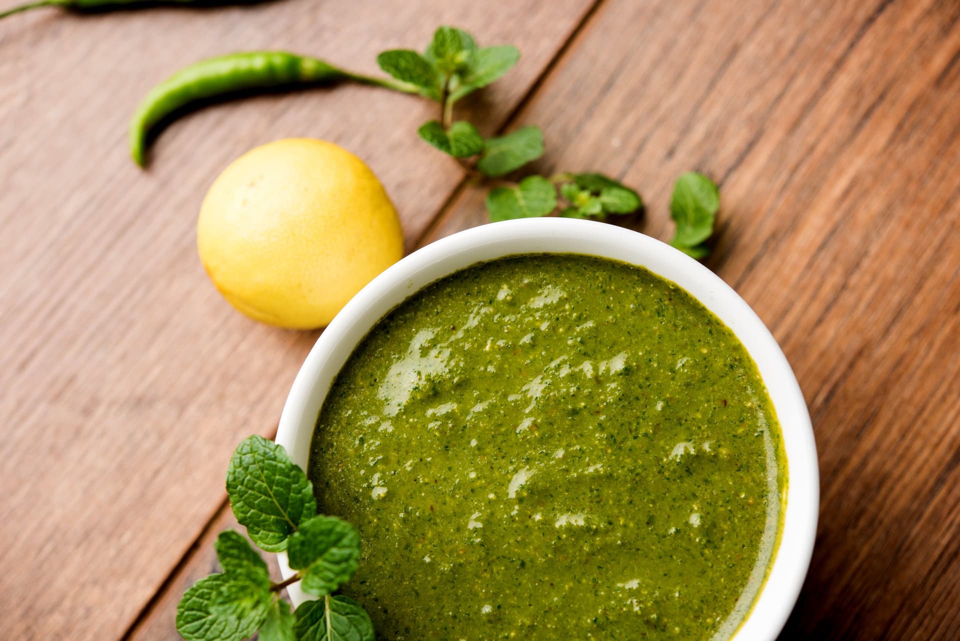 Bowl of fresh mint sauce with mint leaves and lemon