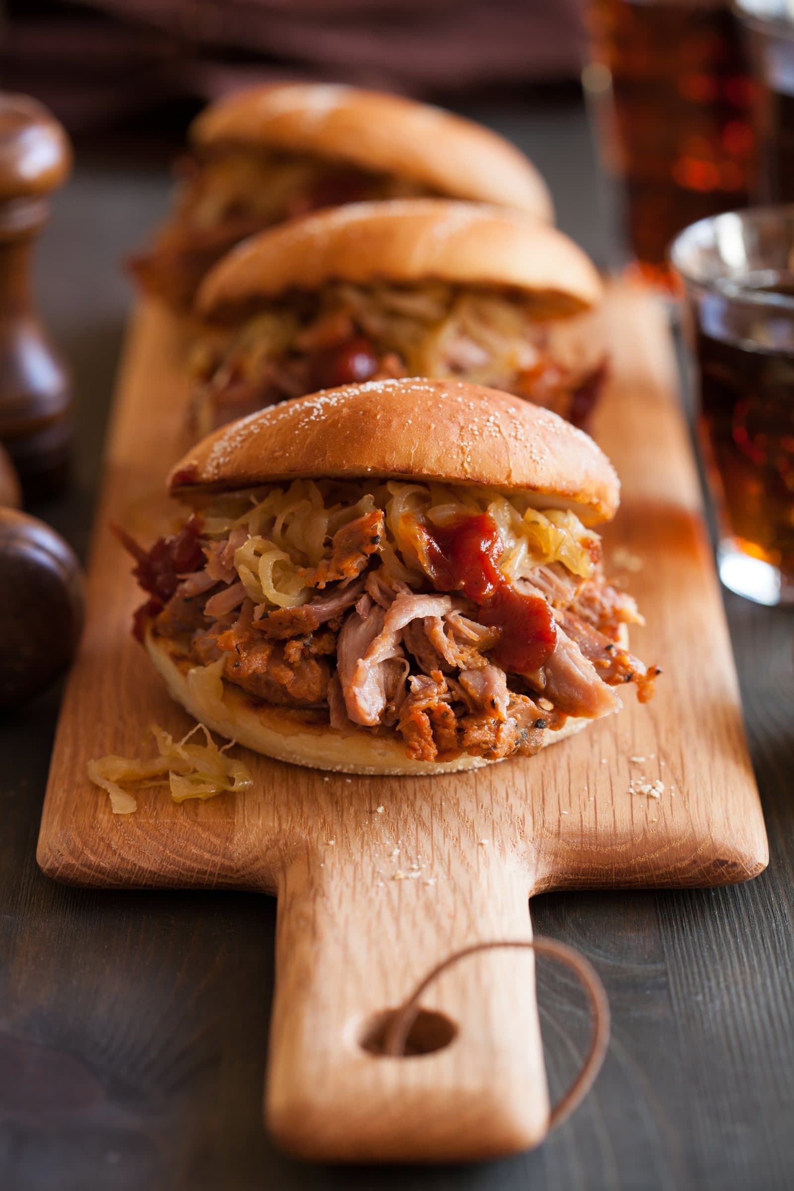 Pulled pork rolls with onions and sauce on a wooden serving board